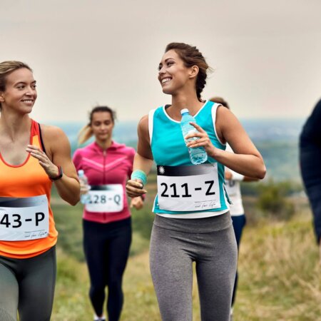 Young happy athletic women running a marathon in nature.